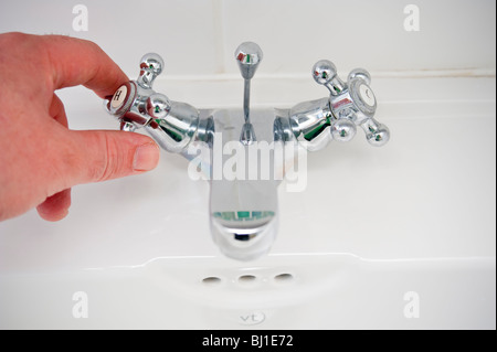 A MODEL RELEASED picture of someone turning the hot tap on in the uk Stock Photo