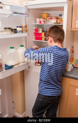 A MODEL RELEASED picture of a 10 year old boy raiding the fridge in the uk Stock Photo