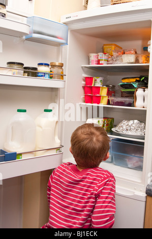 A MODEL RELEASED picture of a 6 year old boy raiding the fridge in the uk Stock Photo