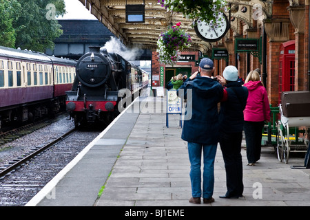 Steam engine 48305 enters Loughborough station as enthusiats look on Stock Photo