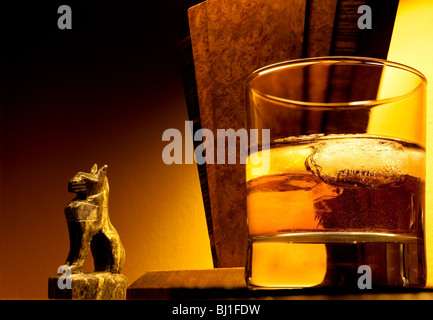 Warm image of art deco lamp and ornament with glass of whiskey in foreground to support the concept of luxury and relaxation. Stock Photo