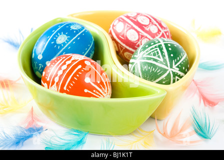 Colorful handmade Easter eggs in saucers with color feathers isolated on white Stock Photo