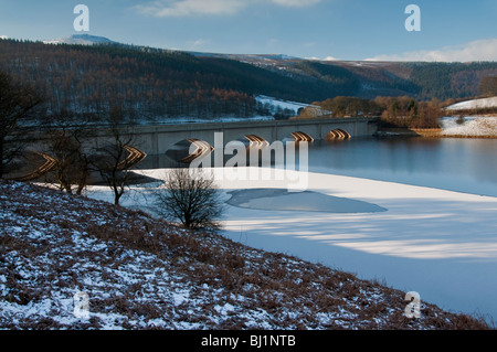 A frozen Ladybower Reservoir in the Peak District with Ashopton Viaduct reflecting the morning sun beneath the arches. Stock Photo