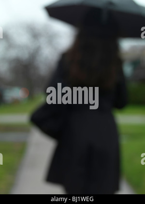 Woman with an umbrella walking along the street on a rainy day Stock Photo