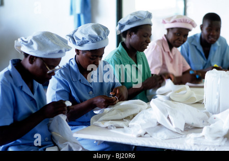 Black female factory workers embroidering white linen Stock Photo