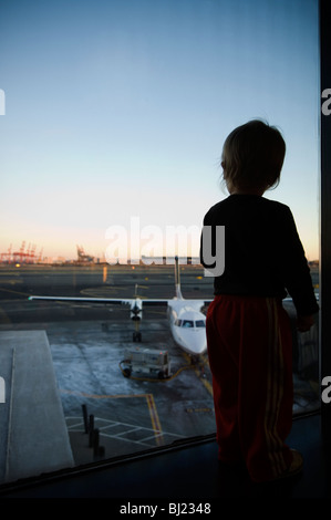 A boy watching a airfield through a window Stock Photo