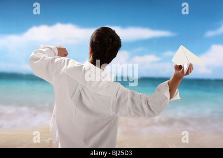 Man playing paper airplane on beach Stock Photo