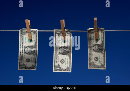 three one dollar bill banknotes hanging on a washing line with blue sky Stock Photo