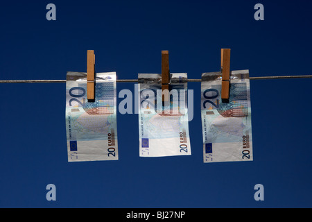 three twenty euro banknotes hanging on a washing line with blue sky Stock Photo