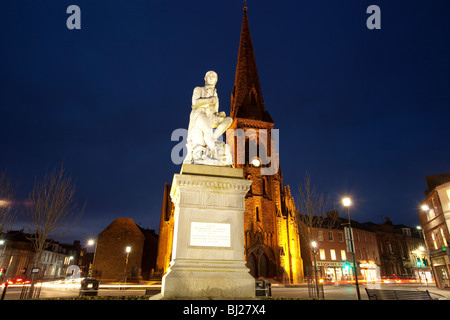 The poet Robert Burns statue in Dumfries town centre with Greyfriars Church behind at night Scotland UK Stock Photo