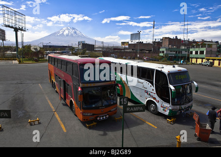 2 bus waiting in the bus station of Arequipa. In the background, the Misti volcano.  The White City, Andes, Peru, South America Stock Photo