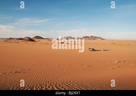 A jeep convoy making camp among the red sands of the Uweinat region of the Sahara Desert, Western Desert, Egypt Stock Photo