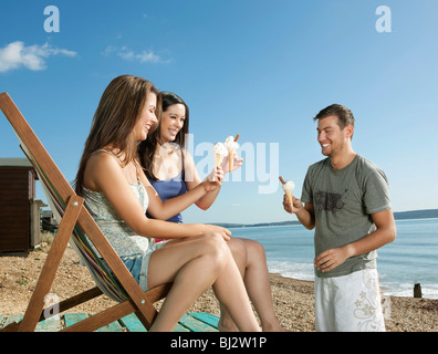 Friends enjoying ice-cream by the sea Stock Photo