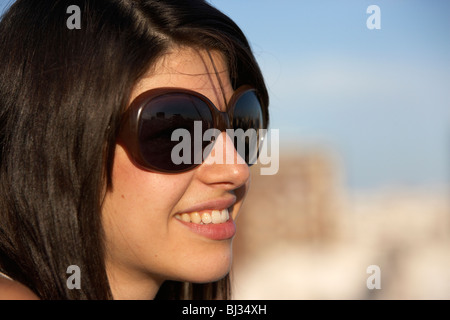 young hispanic latin woman with dark brown hair wearing sunglasses looking out on a hot summer day Stock Photo