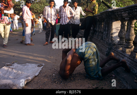 A holy Sadhu man attracts a crowd on the Maidan in central Calcutta, by burying his head to prove hardship and spiritual energy. Stock Photo