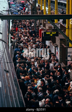 During the evening rush hour, hundreds of rail commuters are queuing to board a Thameslink train which has just arrived. Stock Photo
