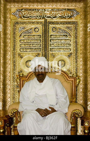 Sudanese President, Omar Hassan Ahmad al-Bashir is seated against a gold leaf backdrop of Islamic texts in his palace. Stock Photo