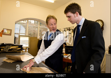 Master tailor Thomas Mahon teaching his new apprentice the trade of tailoring at his Carlisle base Warwick Hall, Cumbra uk Stock Photo