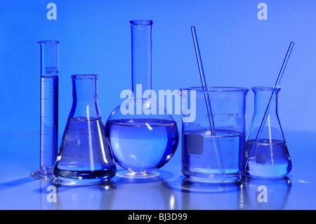 Laboratory glassware in blue light over reflective table Stock Photo