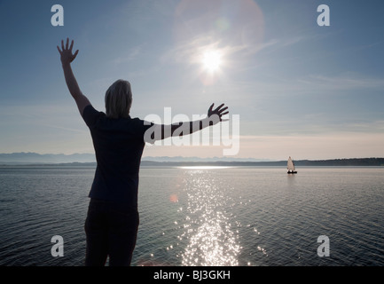 man watching the sun set over a lake Stock Photo