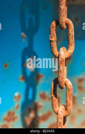 Rusty steel chain links in sunshine against rusty blue background Stock Photo
