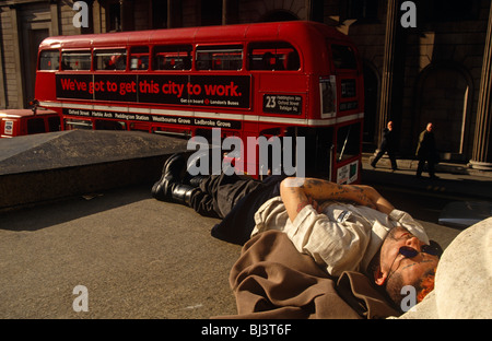 A man is lying down on the steps of Royal Exchange opposite the Bank of England in the City of London. Stock Photo
