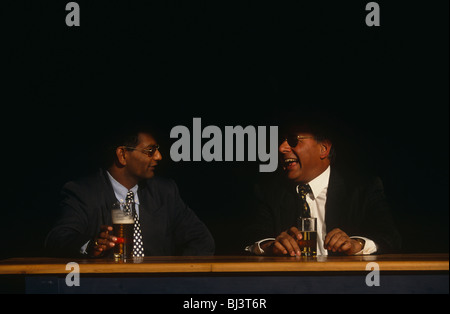 Two businessmen of Asian descent share a joke at a bar in the City of London. Stock Photo