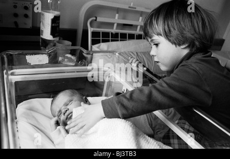 A two and half year-old girl meets her sleeping baby brother for the first time on his actual birthday. Stock Photo