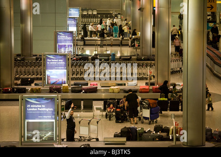 Airline passengers awaiting the arrival of their baggage in the baggage reclaim hall in the arrivals of Heathrow Airport's T5. Stock Photo