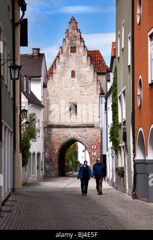 Couple walking up street with archway of Old City Gate in Landsberg am Lech, Bavaria Germany Stock Photo