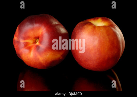 Two red nectarine peaches isolated on black background Stock Photo