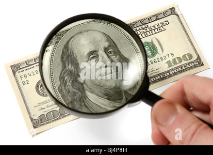Hundred dollar bill under a magnifying glass is being inspected Conceptual photo isolated on white background Stock Photo