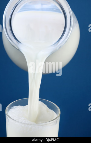 Milk pouring from jar into the glass Stock Photo