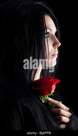 Brunette goth woman with rose portrait. Dark colors. Stock Photo