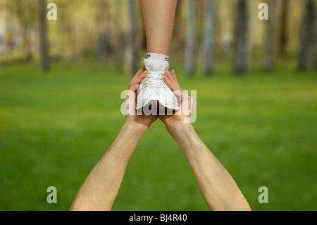 Two strong male hands holding one female foot. Teamwork, support, help, gymnastics, competition concepts. Stock Photo