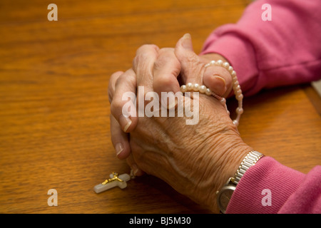 Praying hands of a senior woman with rosary beads Stock Photo
