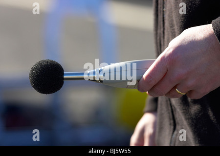 mans hand holding sound level meter with baffle the meter is used to measure maximum noise level compliance Stock Photo