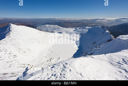 Winter View over the frozen Red Tarn from Helvellyn, Catstye Cam on the left & Striding Edge on the right, English Lake District. Stock Photo