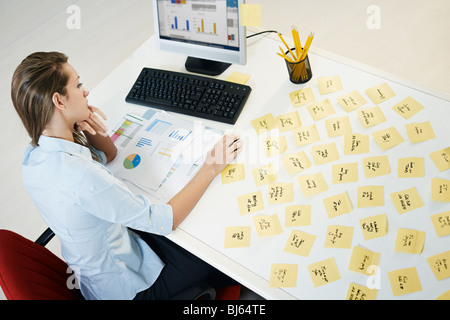 tired business woman with adhesive notes on table. High angle view Stock Photo