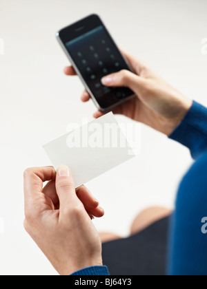 businesswoman holding blank business card and dialing numbers on mobile phone Stock Photo