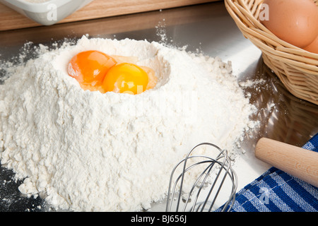 bakery scene - two egg yolks on a heap of wheat flour, surrounded by baking utensils Stock Photo