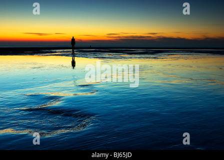 Colouful sunset at Crosby beach, with one Of Anthony Gormly Statues Stock Photo