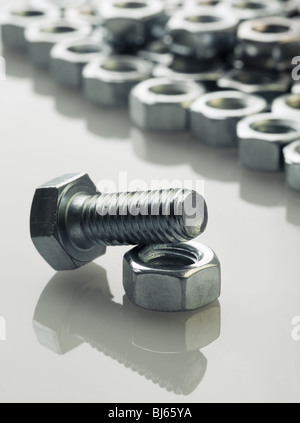 screw bolts and nut on reflective white surface. Stock Photo