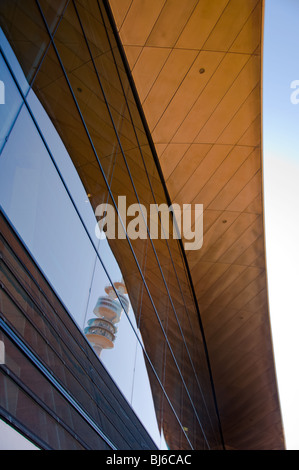 Munich's Olympic tower is reflected off of the modern glass of the BMW Welt building. Stock Photo