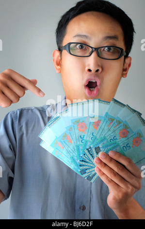 A Malaysian man pointing to money with surprising face Stock Photo