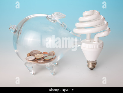 Low-energy light bulb and a glass piggy bank with saved money Stock Photo