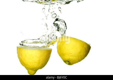Cut yellow lemon splashing to fresh water Stock Photo