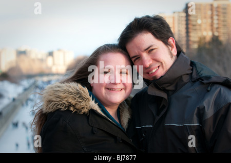 A young smiling couple pose in front of Ottawa's Rideau Canal- the worlds longest skating rink. Stock Photo