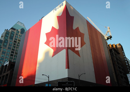 A Huge building wrapped on two sides with the Canadian National flag on the corner of Georgia street and Howe street.