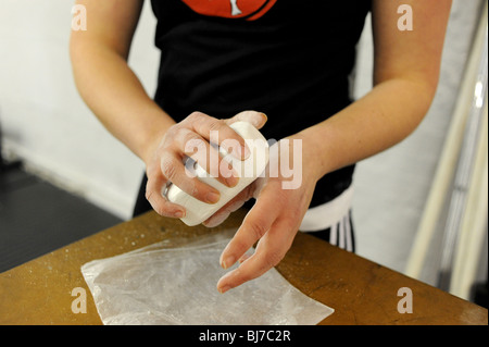 Female weightlifter rubs chalk on to her hands to help with grip Stock Photo